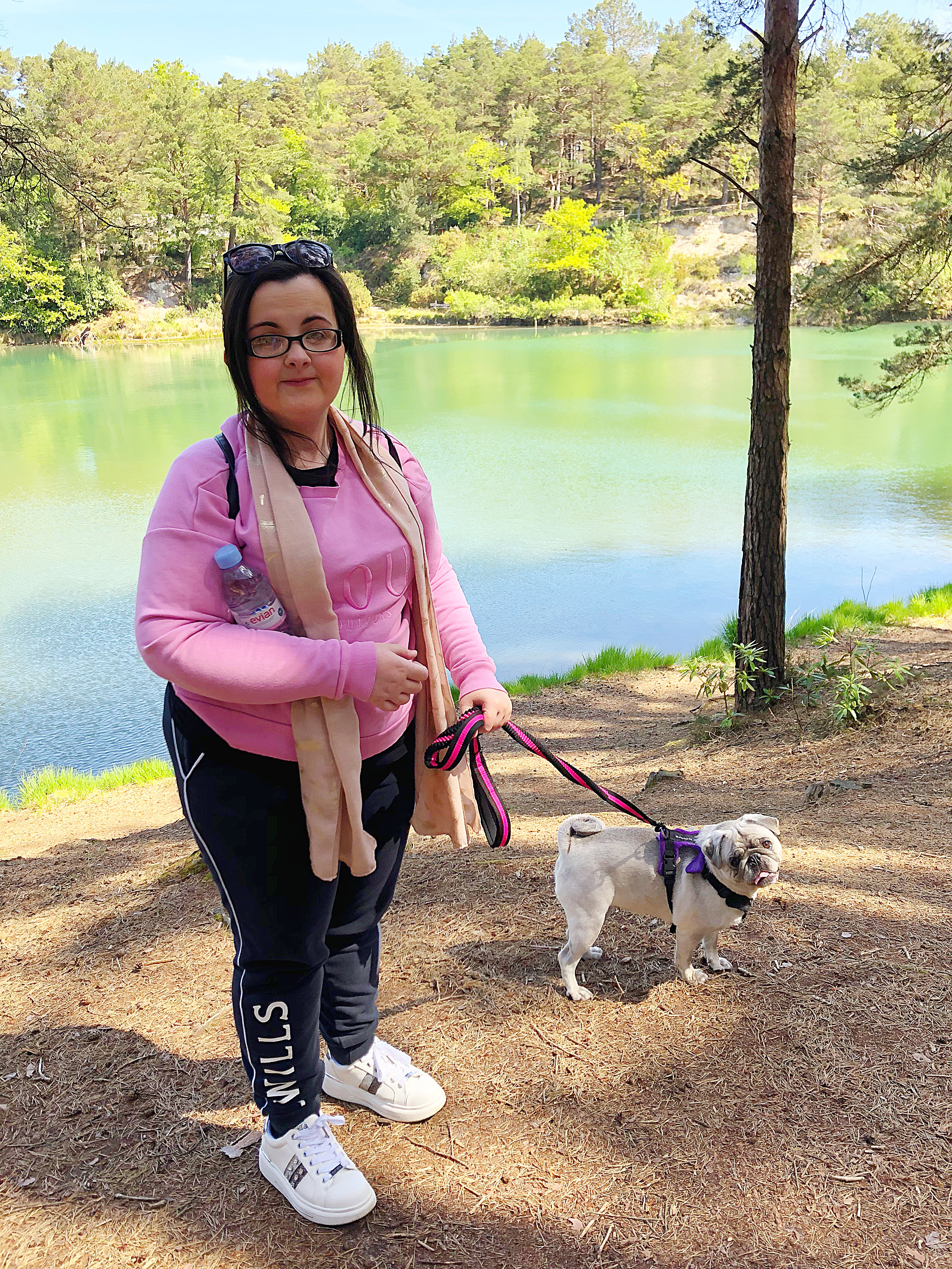 Tasmin, a young women with MCAS pictured by a lake, walking her dog Masie