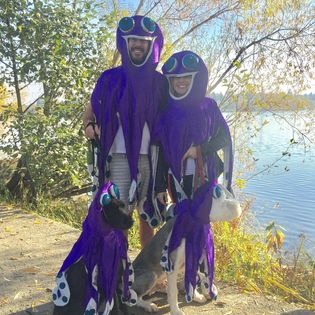 Two people dressed as octopus standing by a lake