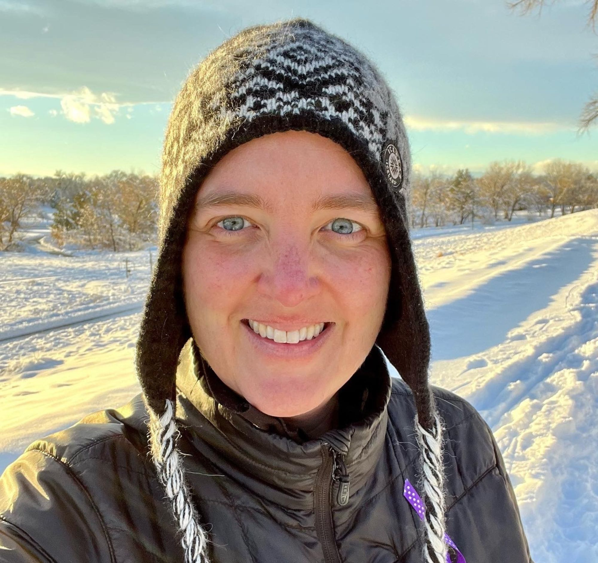 A women living with MCAS in the snow, wearing a hat