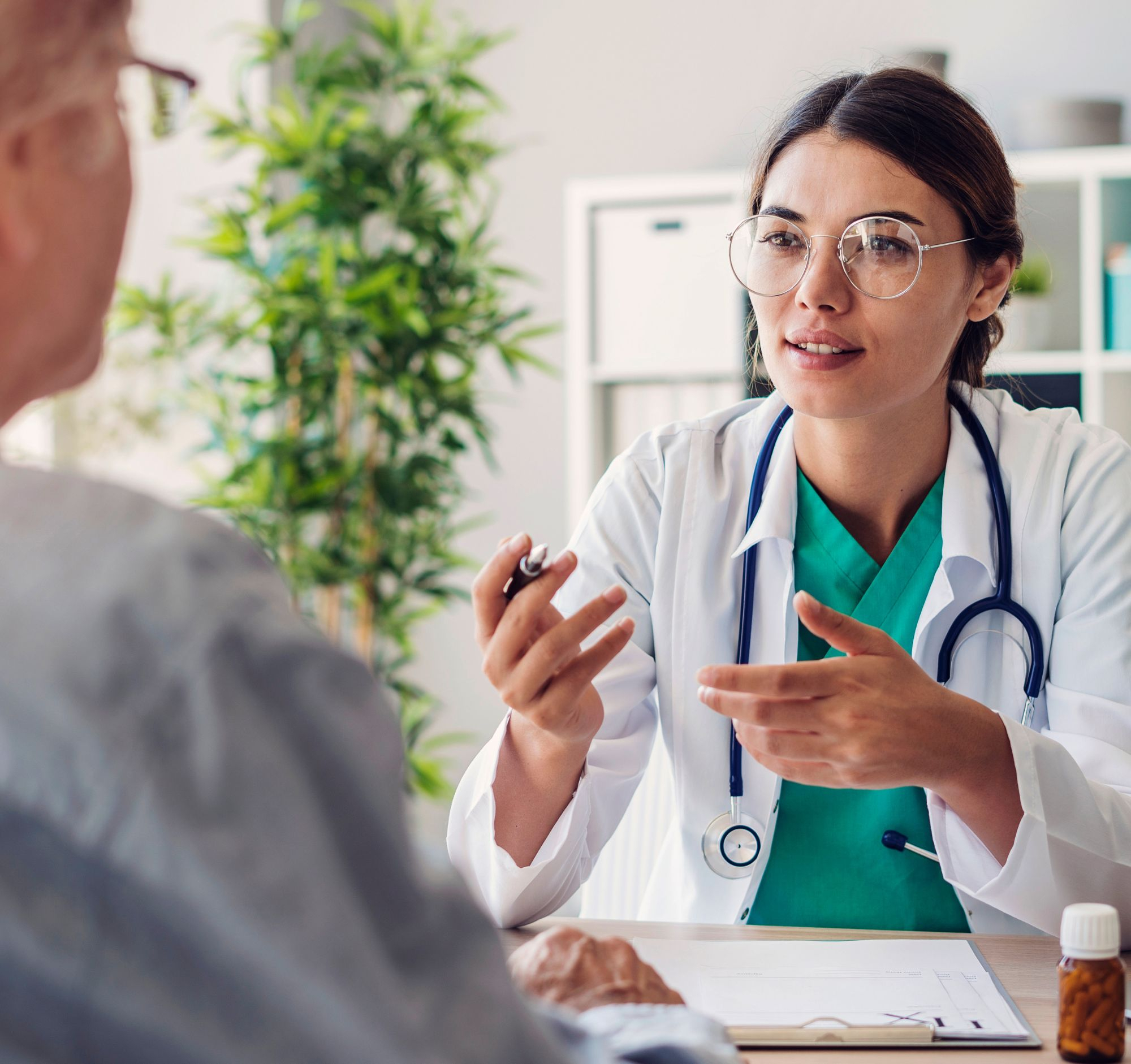 A doctor, wearing a stethoscope around her neck talking with a patient