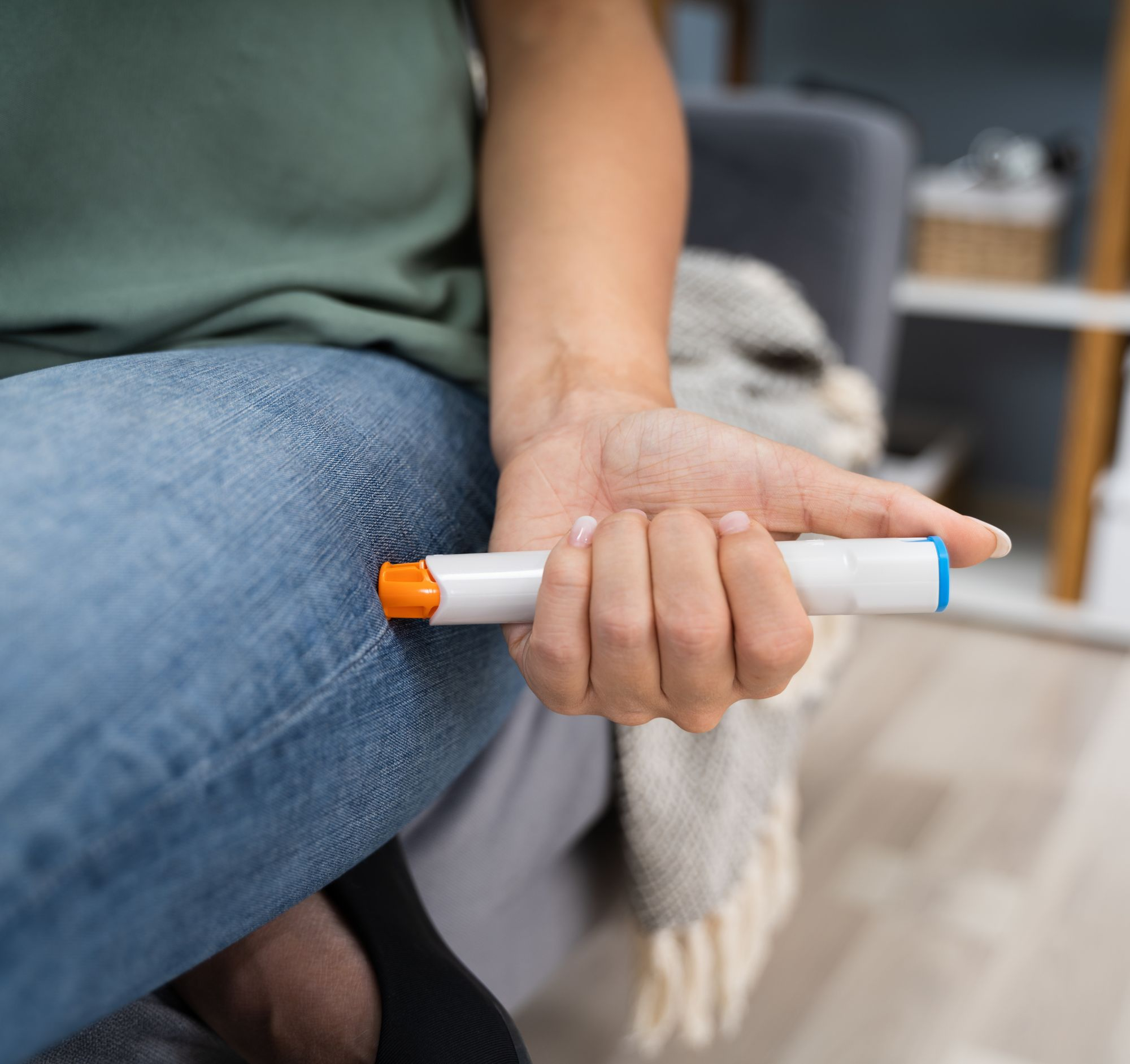 An epi-pen bring injected into a women's leg through her jeans
