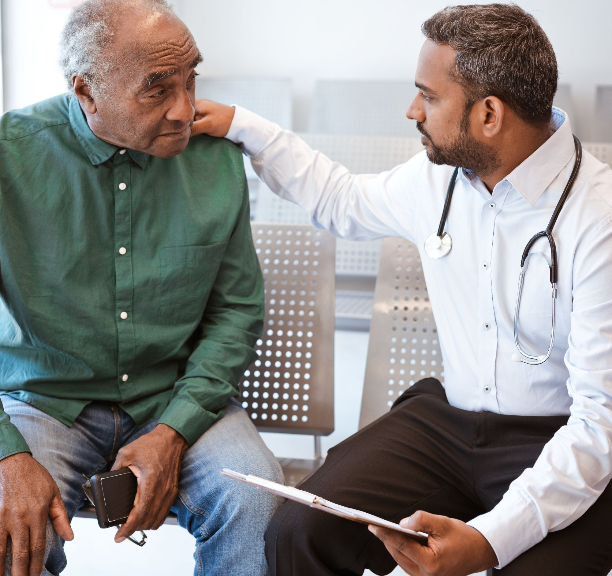 A doctor talking with a patient, with his hand on the patient's shoulder